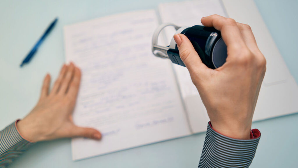 Hands prepare to notarize a page with a notary stamp