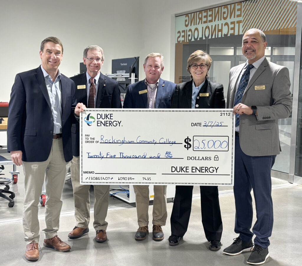 Four men and a woman hold up a large $25,000 check from Duke Energy.