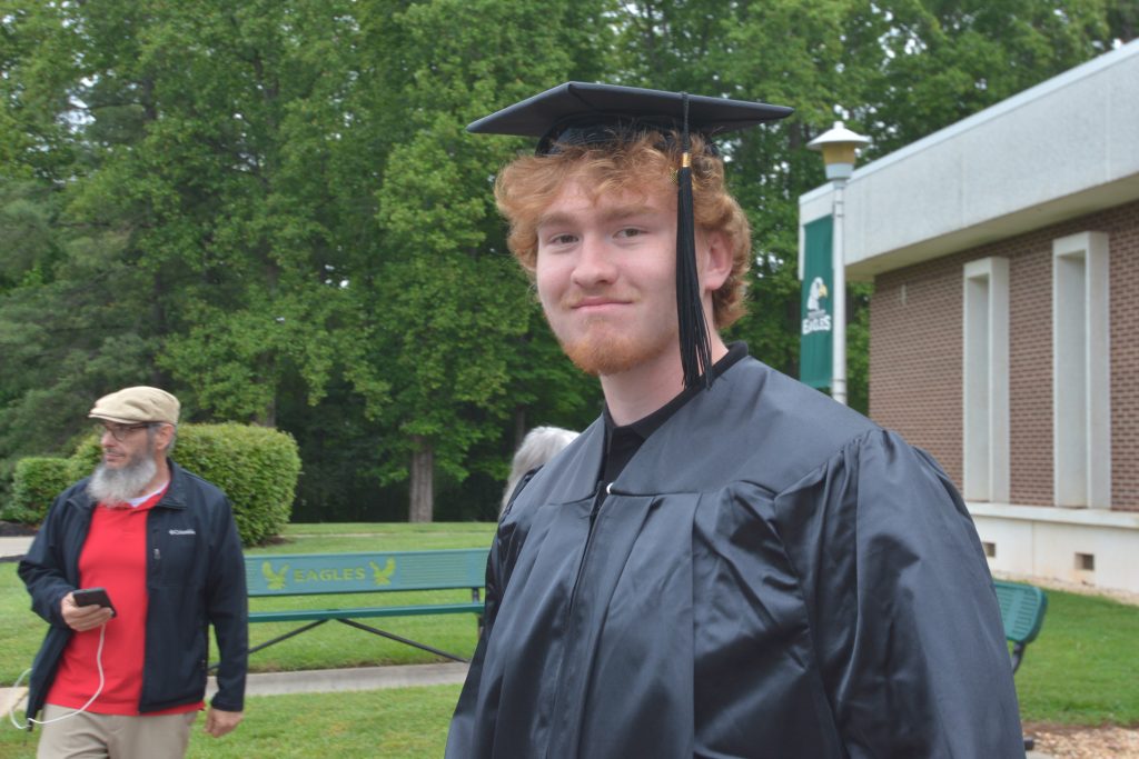 Male graduate smiles as he walks out of the gym