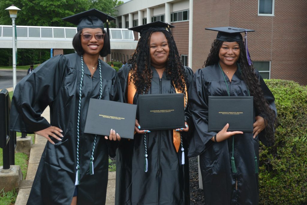 Three Black female graduates pose with their degrees