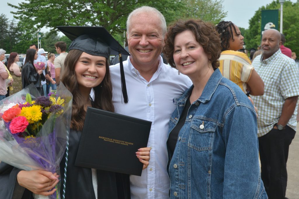 A female graduate smiles with her family after the ceremony