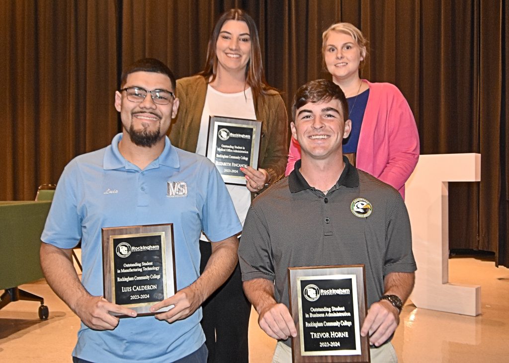 Picture of four students holding plaques.