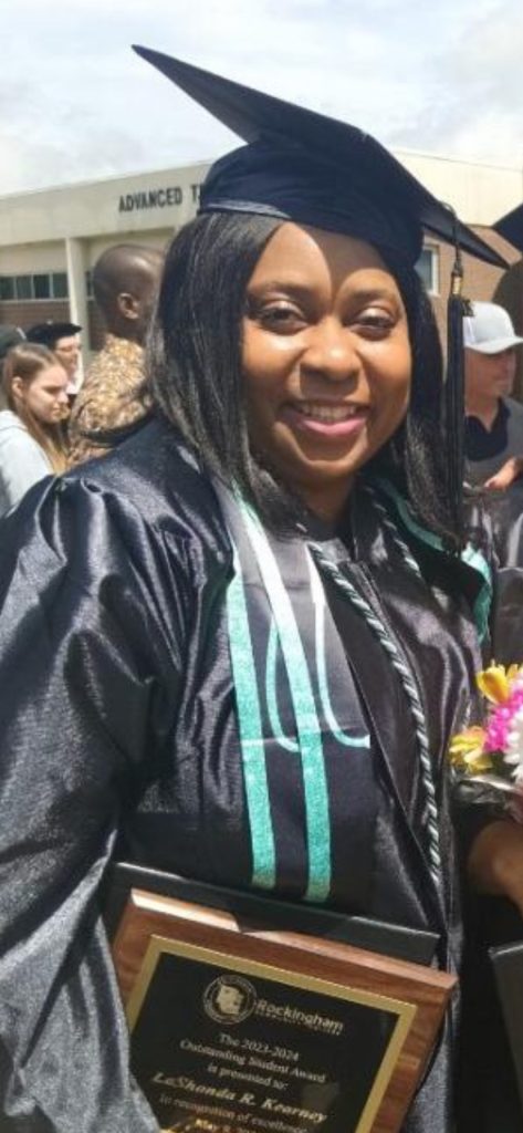 A graduate smiles in her cap and gown on graduation day.