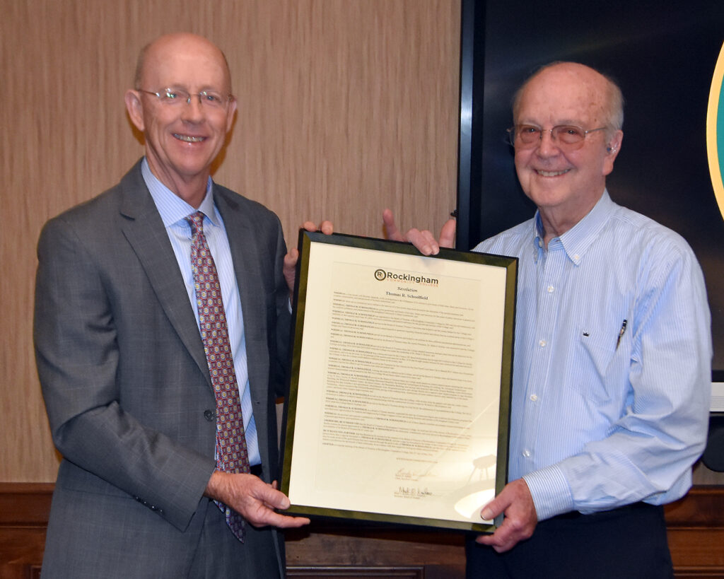 Two men hold up a framed resolution.