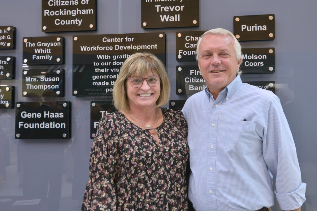 A couple stands in front of a wall of donor plaques.