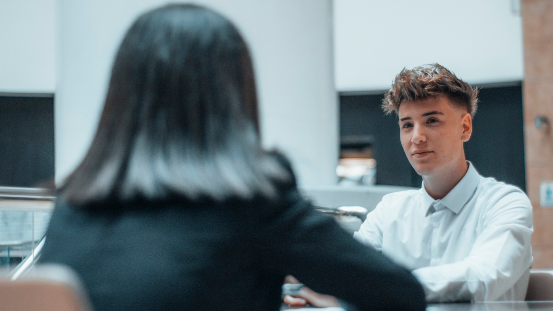 A young man being interviewed by a woman at a desk