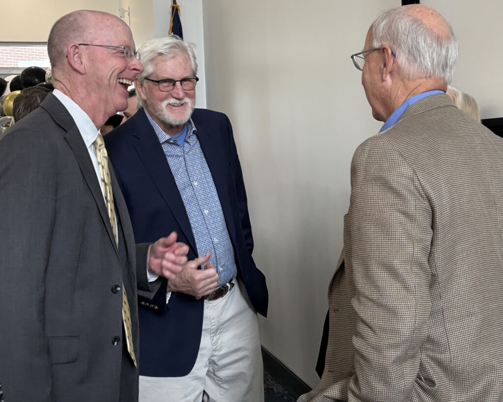 Three men laugh and talk