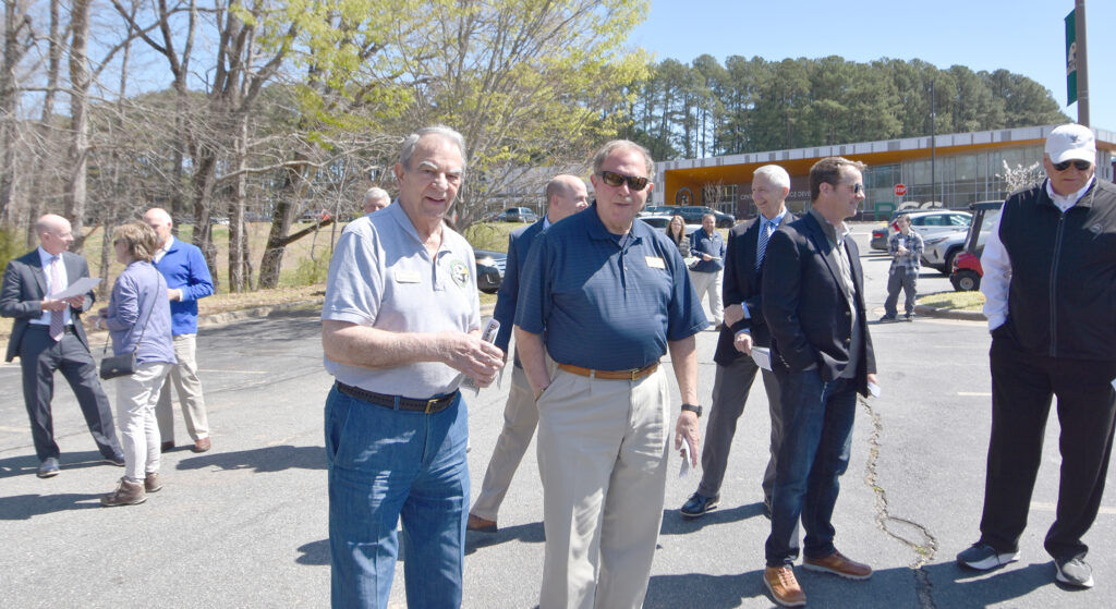 A group of adults gathered in a parking lot.