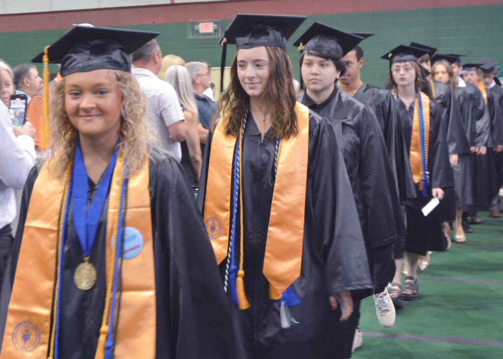 Students in caps and gowns march into their graduation ceremony.