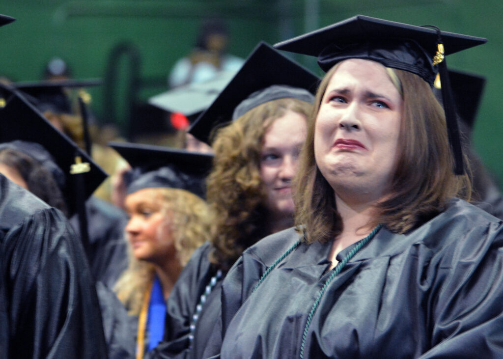 A female graduate has tears in her eyes as she looks toward the audience during the ceremony.