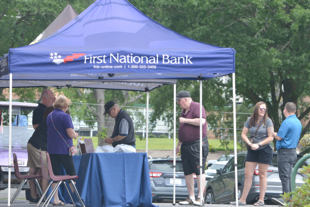 People stand in line at a First National Bank tent.