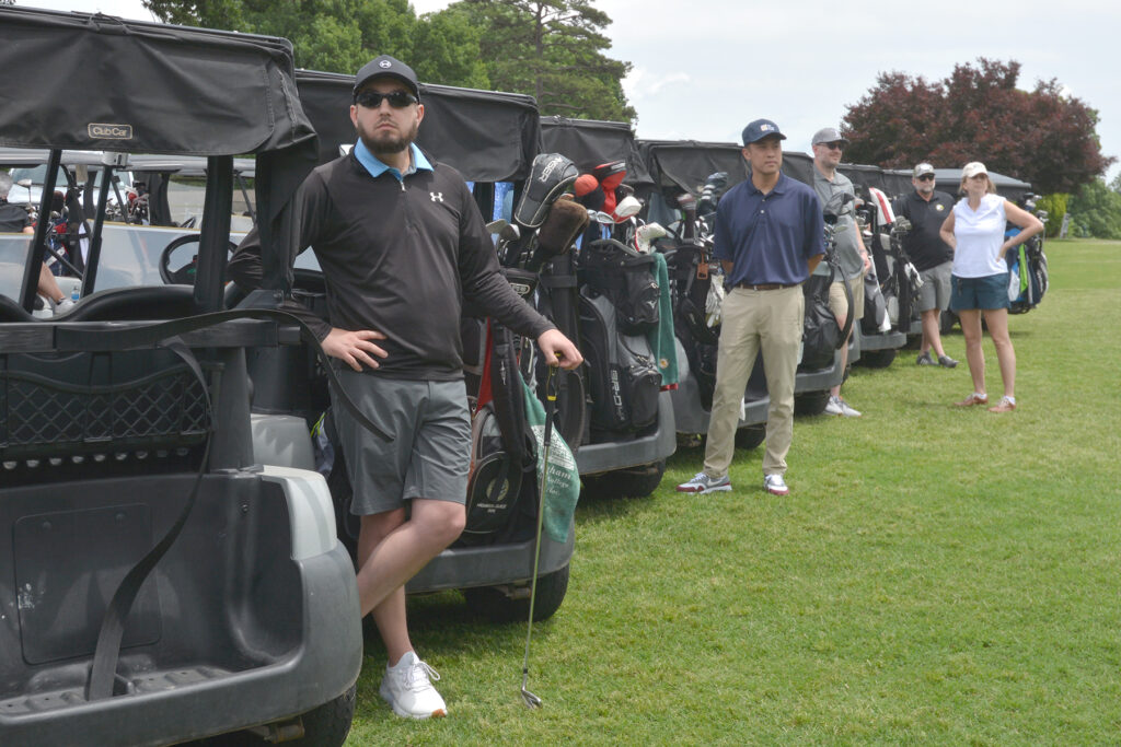 Golfers stand behind their carts.