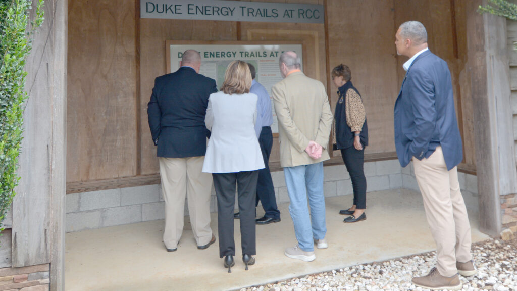 Four men and two women examine a campus map in a trail kiosk.