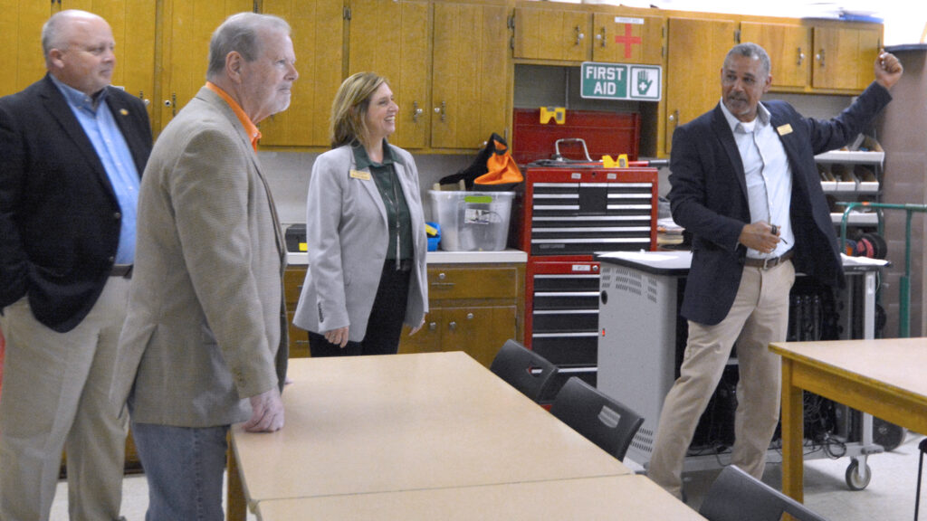 Three men and a woman actively engage in a discussion in a classroom.