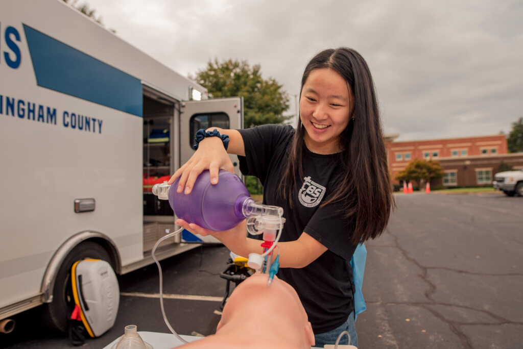 A young girl pumps air into a mannequin's mouth