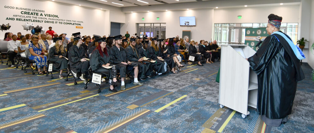 An audience listens to a woman speak at a podium.