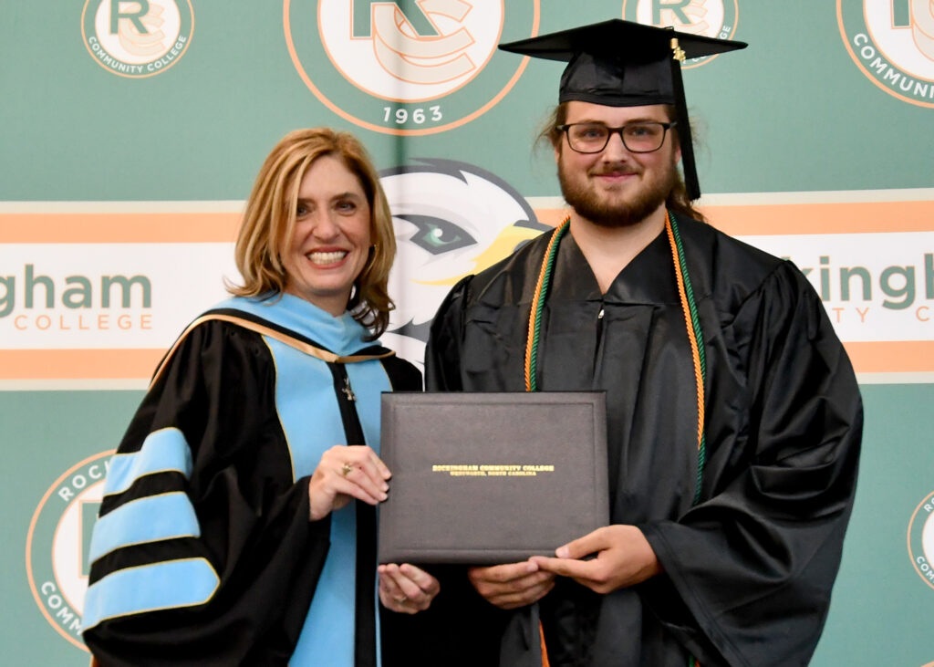 A woman and a graduate show off a diploma.