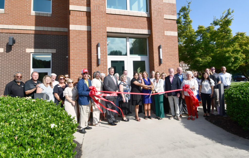 A group of people cut a ribbon with a giant pair of scissors