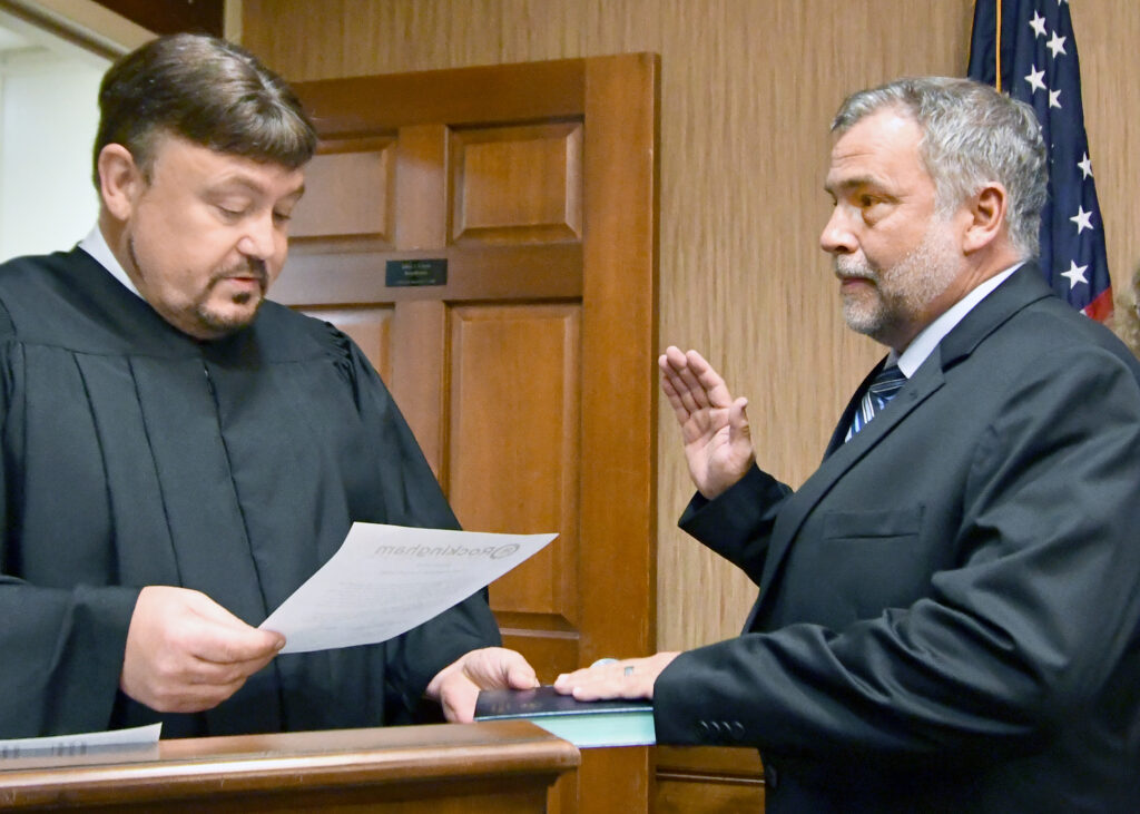 A man administers an oath of office to another man.
