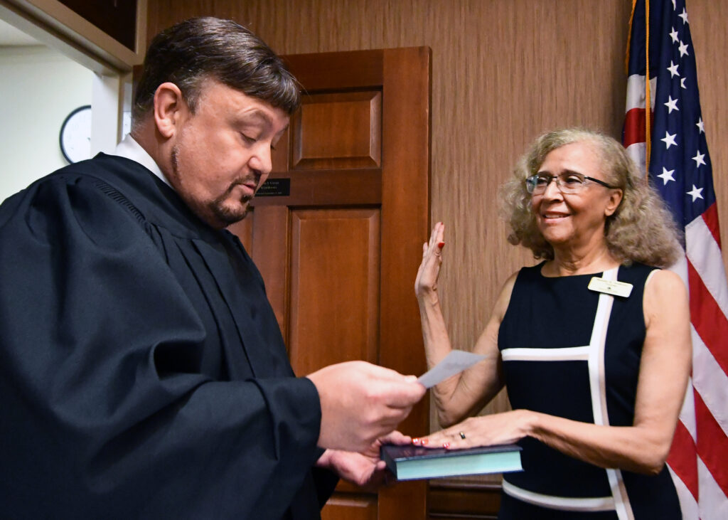 A man administers an oath of office to a woman.