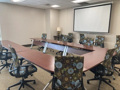 Picture of ADT 103 class room. U shaped table with chairs around it and a projector.
