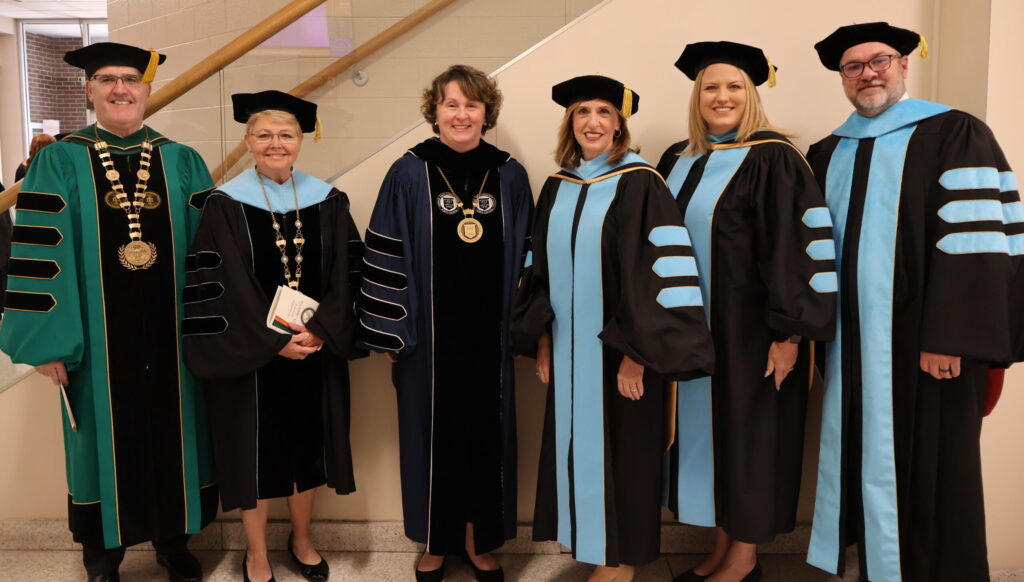 A group of two men and four women in academic regalia
