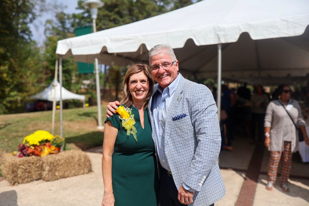 A man and woman stand close and smile.