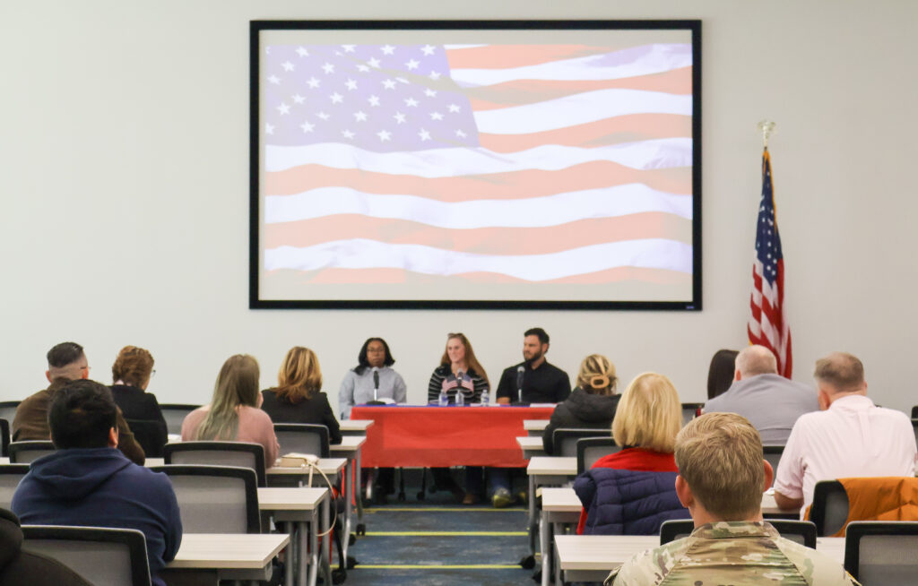 Three student veterans sit on a panel in front of a crowd.