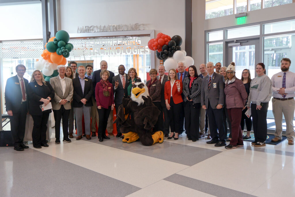 A crowd of people smiles with balloons behind them