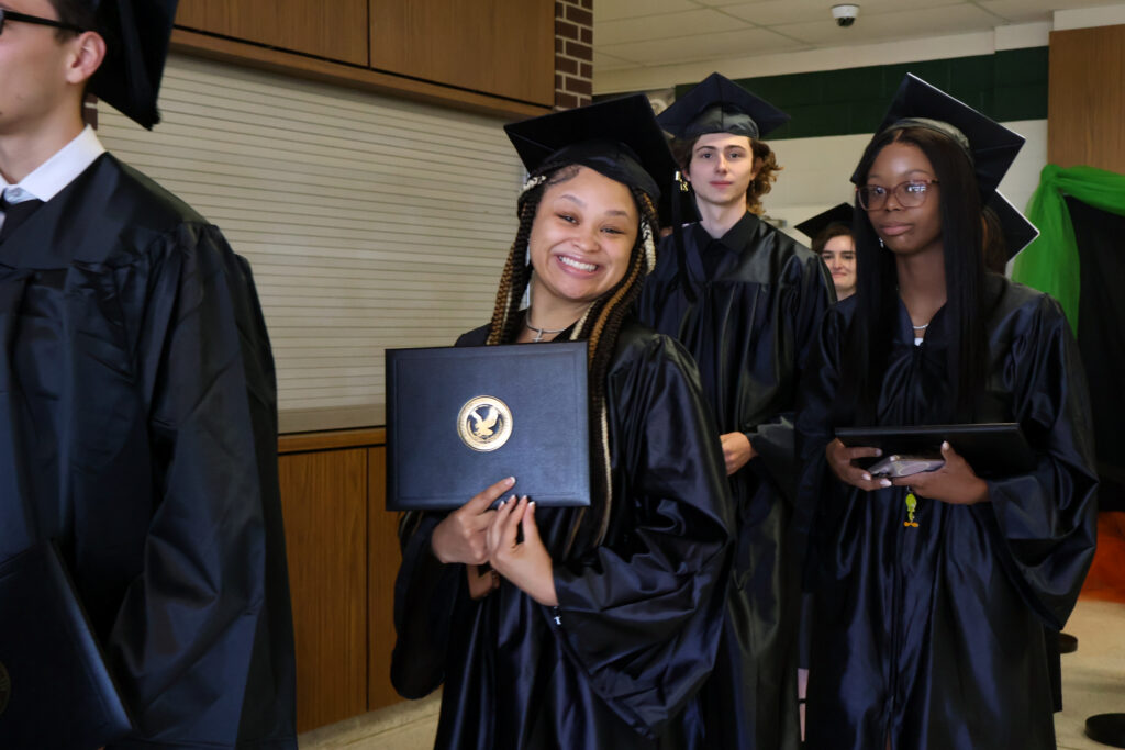 A graduate smiles sweetly with her diploma.
