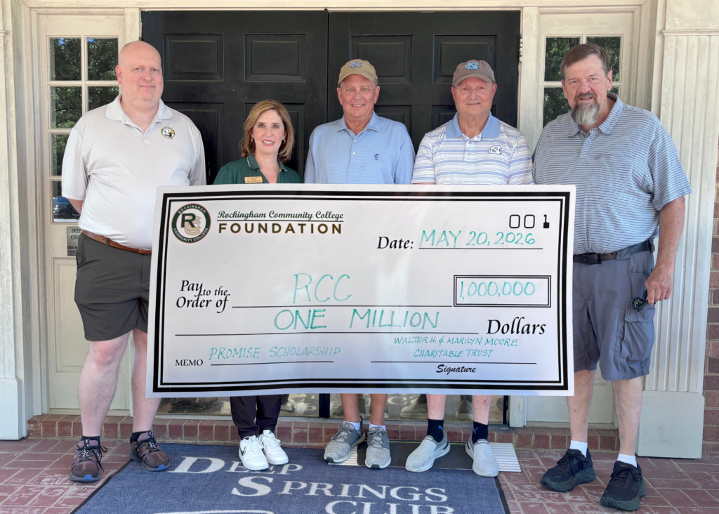 Adults hold up a giant $1 million check.