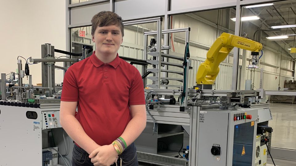 Student smiles by machinery