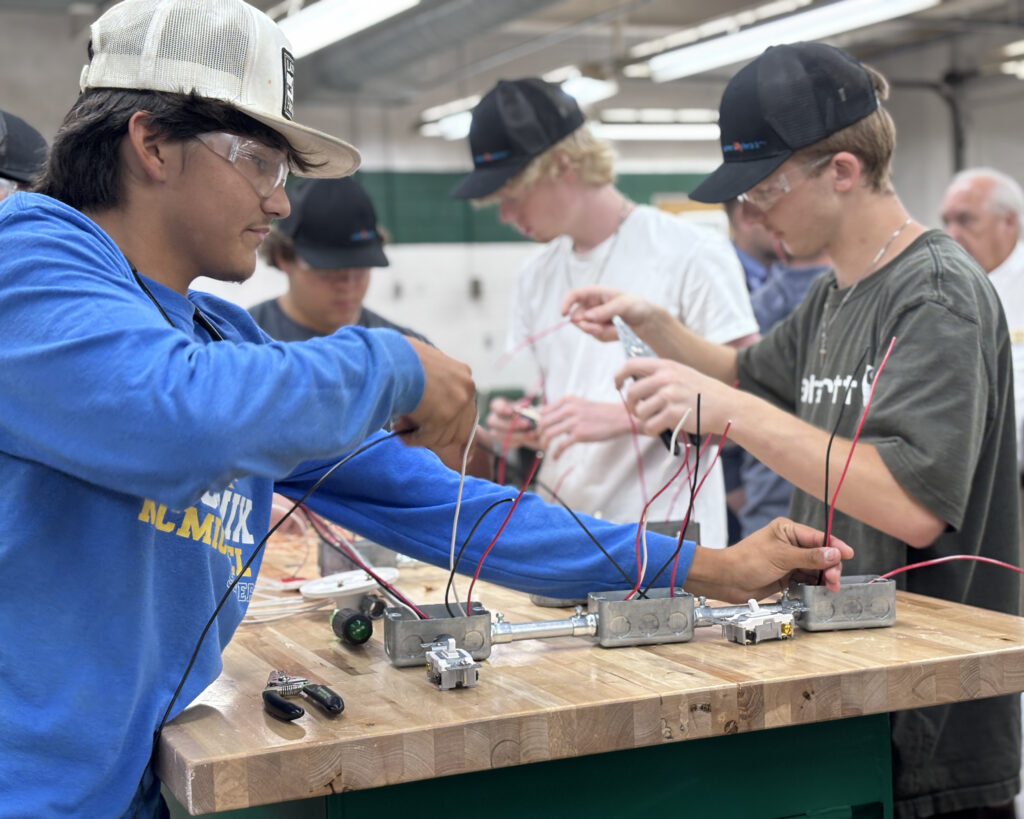 Students at a work table wire electrical sockets.