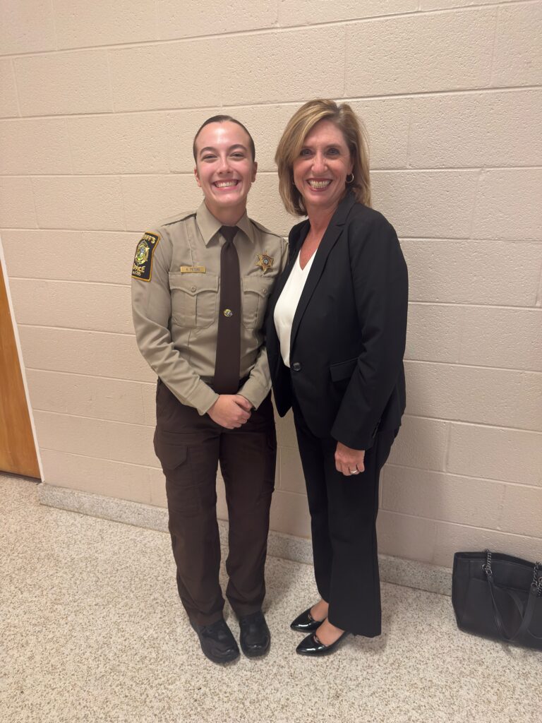 A lady in a law enforcement uniform and a lady in a suit.