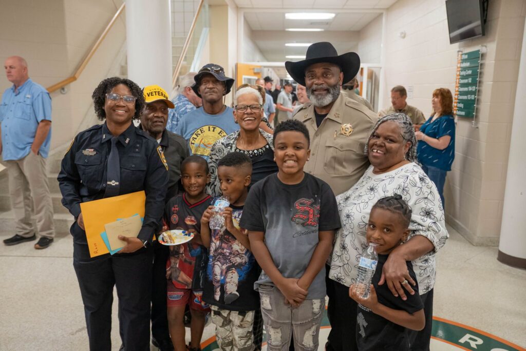 A new female police officer celebrates after BLET graduation with a group that included the Guilford County sheriff.