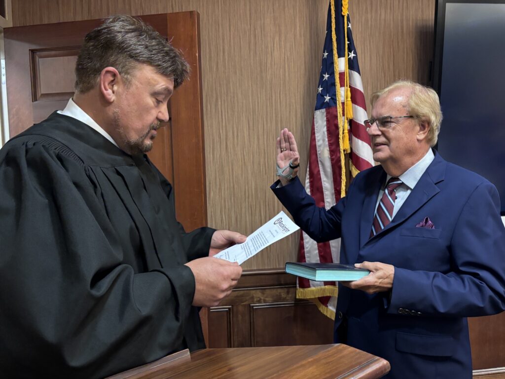 A man administers an oath of office to another man.