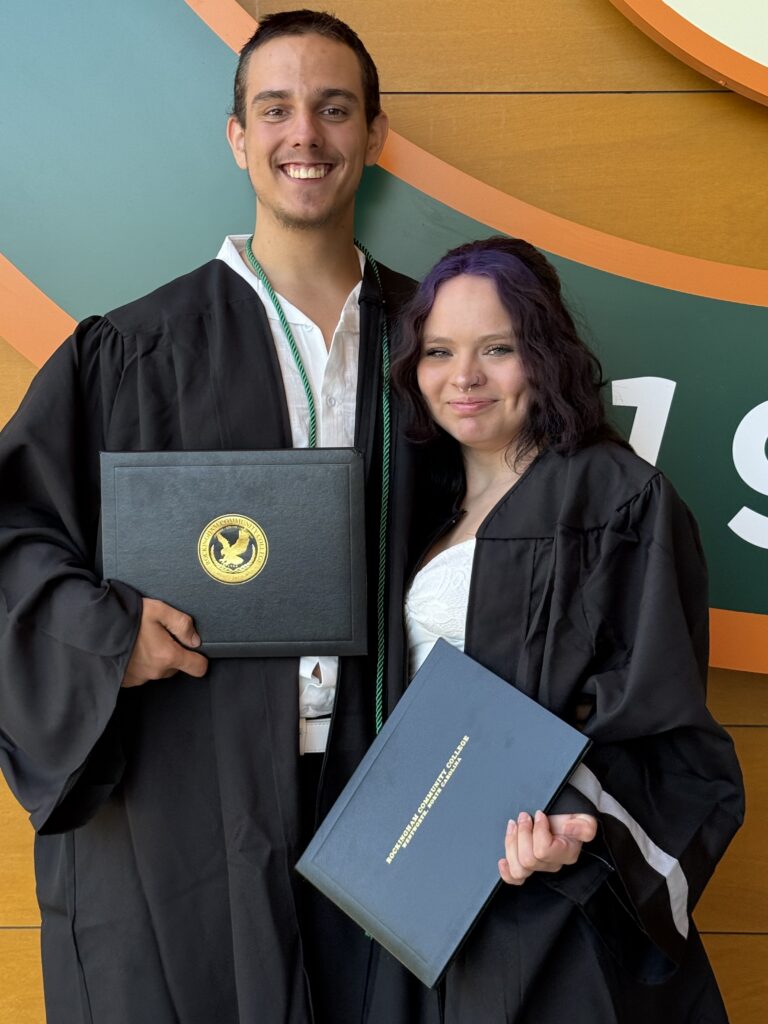 Two CCR Graduates standing for a picture holding their degrees.