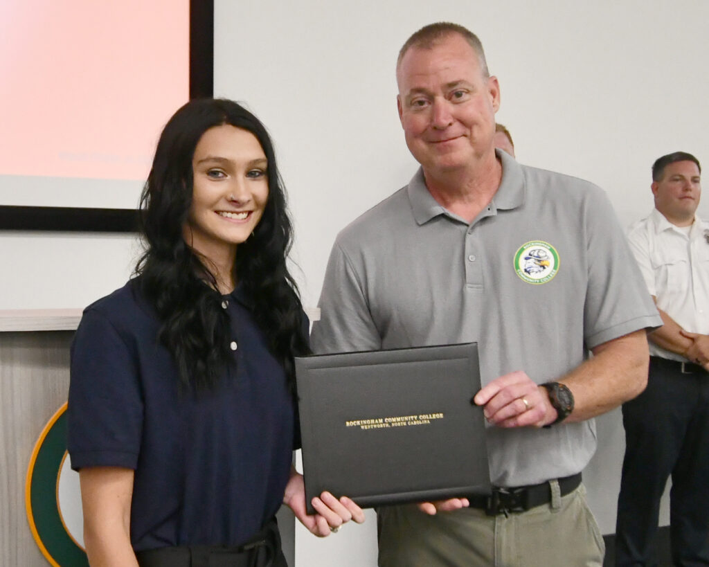 A cadet accepts an award from the Fire Academy director.
