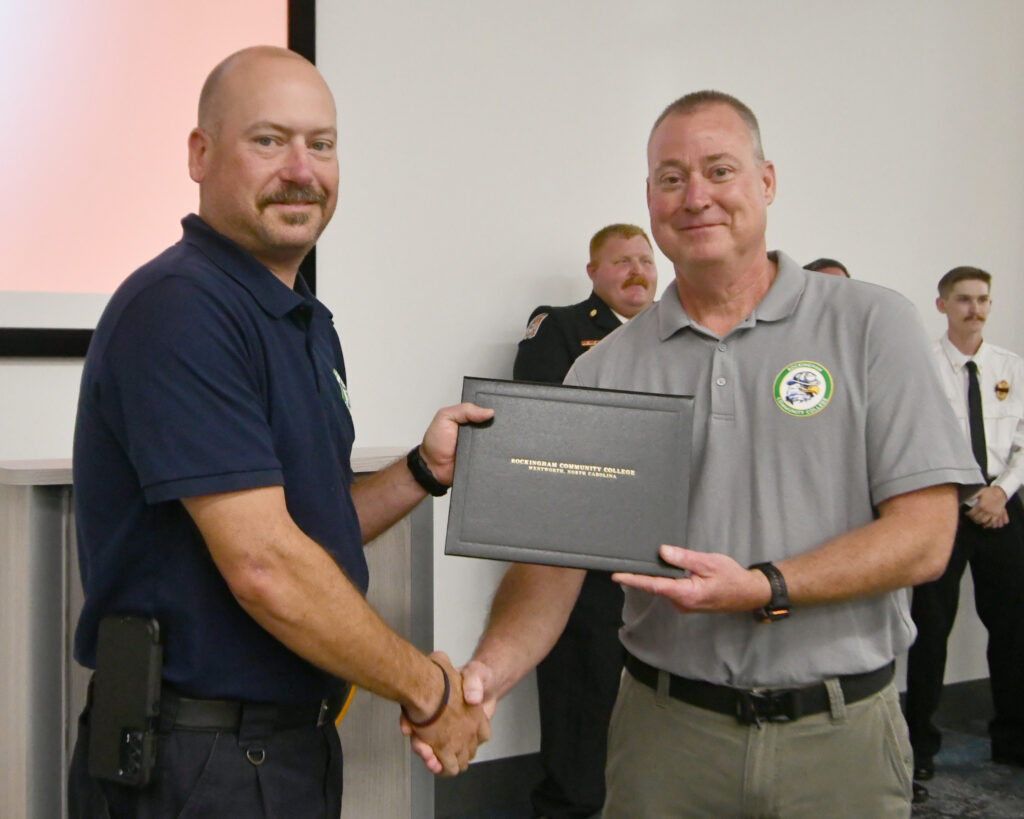 A cadet accepts an award from the Fire Academy director.