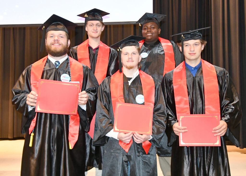 Five students in caps and gowns, on the night they graduated from their apprenticeship program.