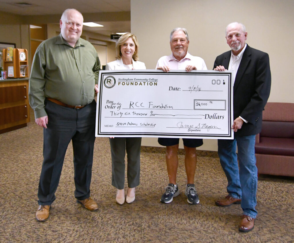A lady and three men hold up a gigantic check for $36,000 for the RCC Foundation for the Steve Adams scholarship.